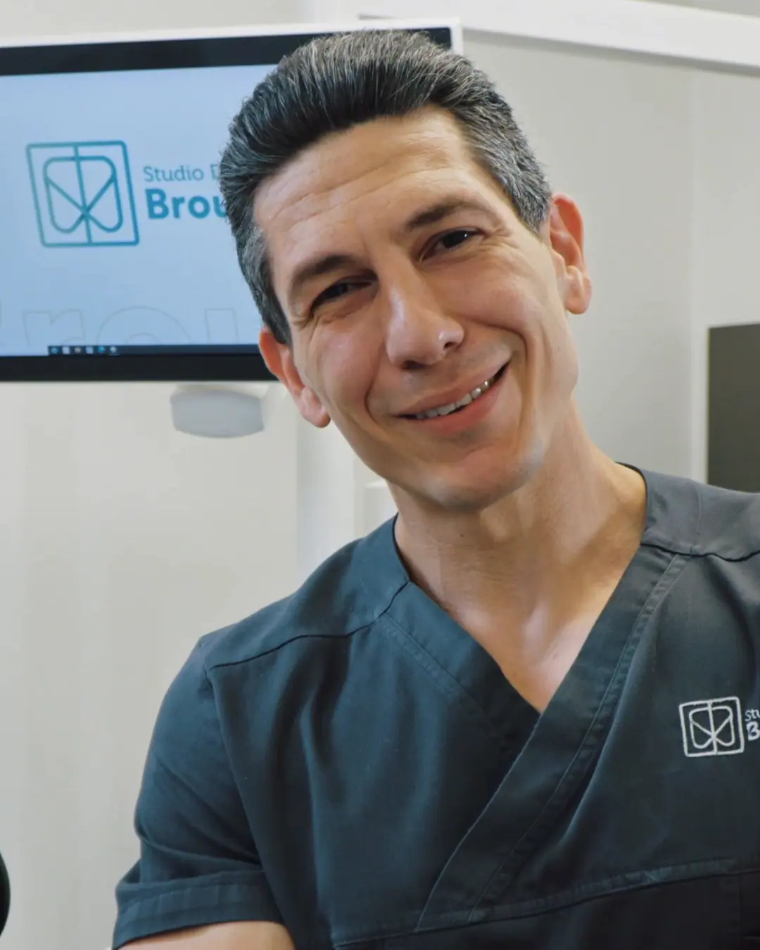 Marco Caburlotto, igienista dentale dello studio, sorride a braccia conserte